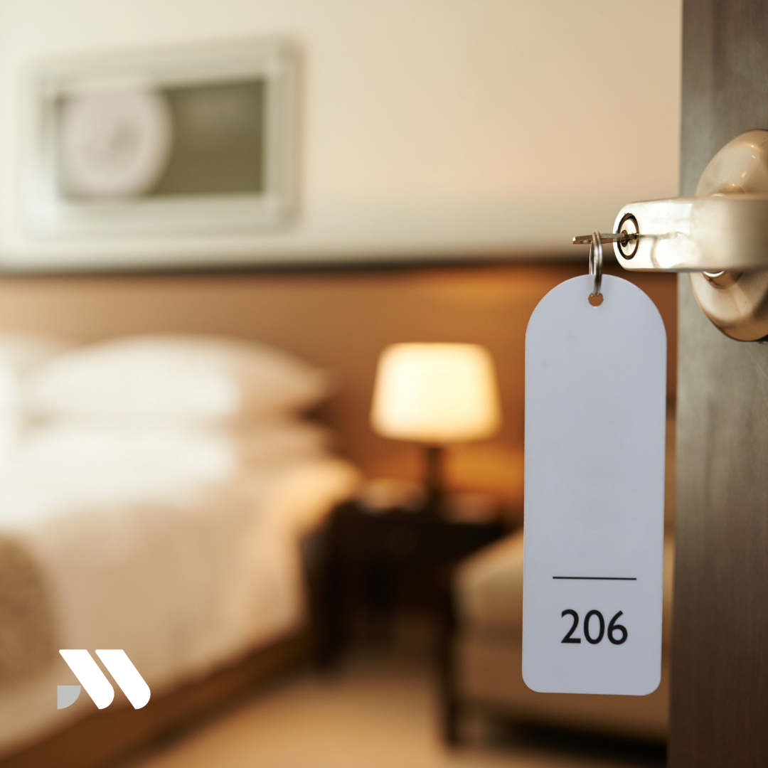 Hotel room key hanging from a door lock, representing temporary lodging expenses that may be covered by Additional Living Expenses (ALE) coverage after a covered homeowners insurance loss.