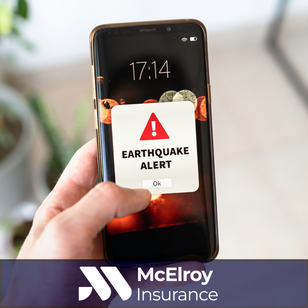 Smartphone displaying an earthquake alert notification with McElroy Insurance branding, highlighting earthquake preparedness and insurance protection for California homeowners.