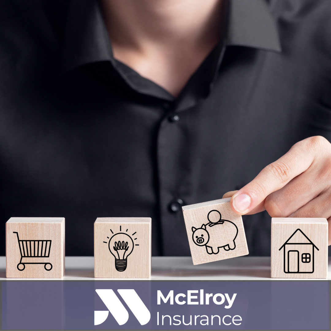 Person placing a piggy bank block between shopping cart, light bulb, and house icons, representing inflation, rising costs, savings, and the importance of maintaining adequate insurance coverage.